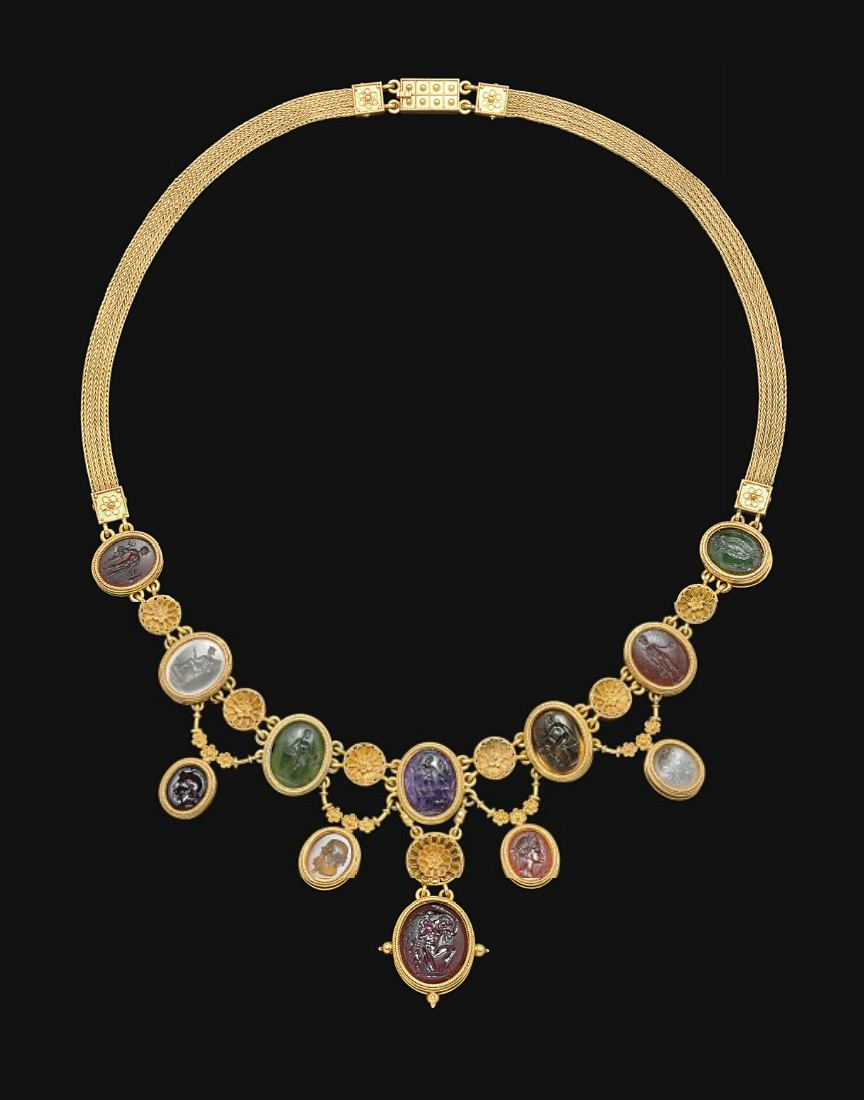 A luxurious gold necklace is clasped on a dark background. The piece is elaborate, featuring a golden chain complemented by a series of round and oval medallions. Each medallion is set with a distinct carved gemstone in a variety of colors such as green, purple, red, and grey, showcasing unique inscriptions or figures.