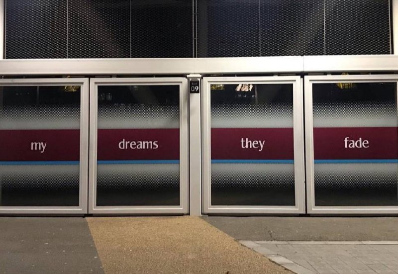 A set of three doors is equipped with frosted glass, each featuring a word that collectively form the sentence 'my dreams they fade.