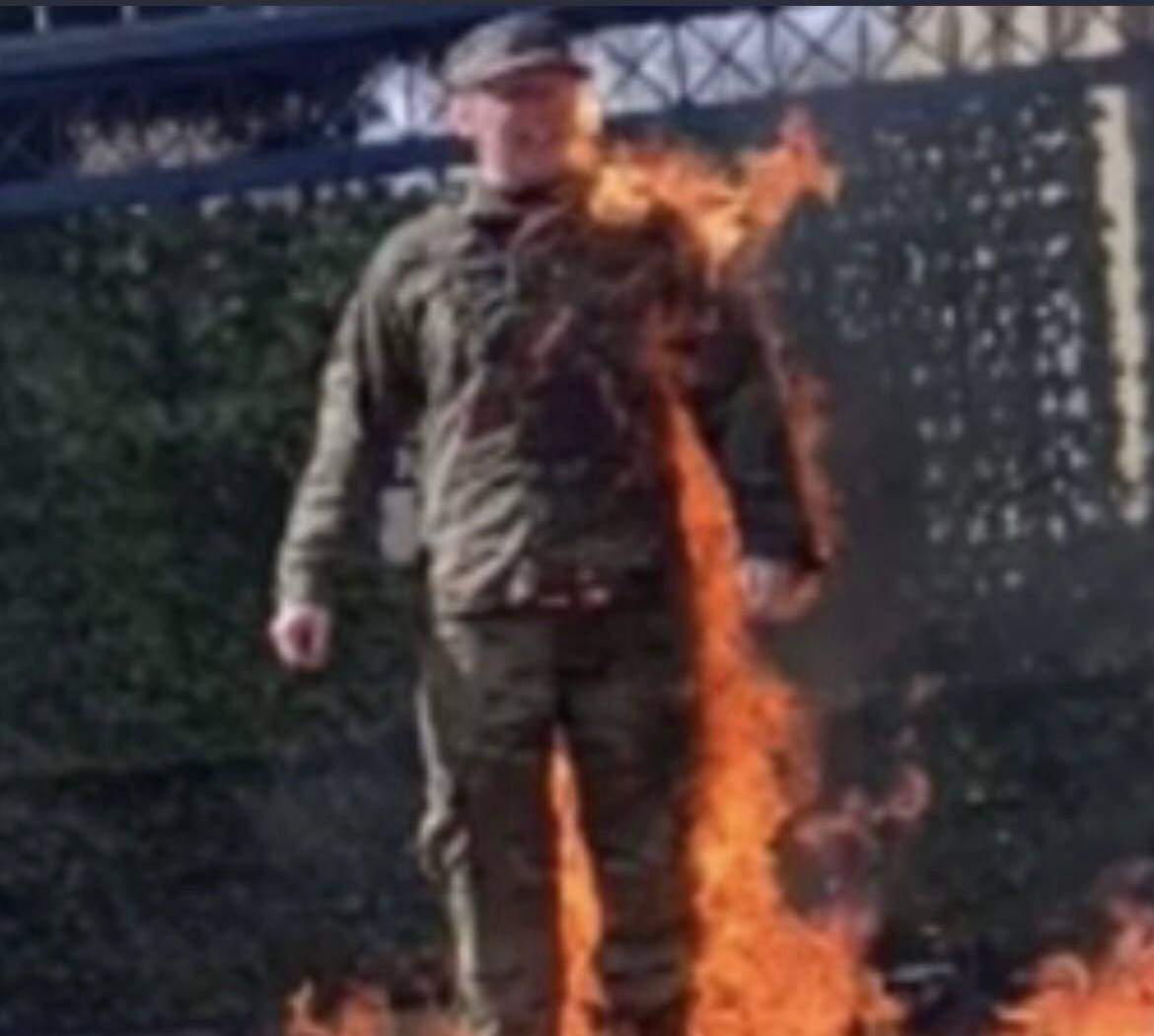 Blurry image, person on fire, military uniform, emergency situation, intense flames