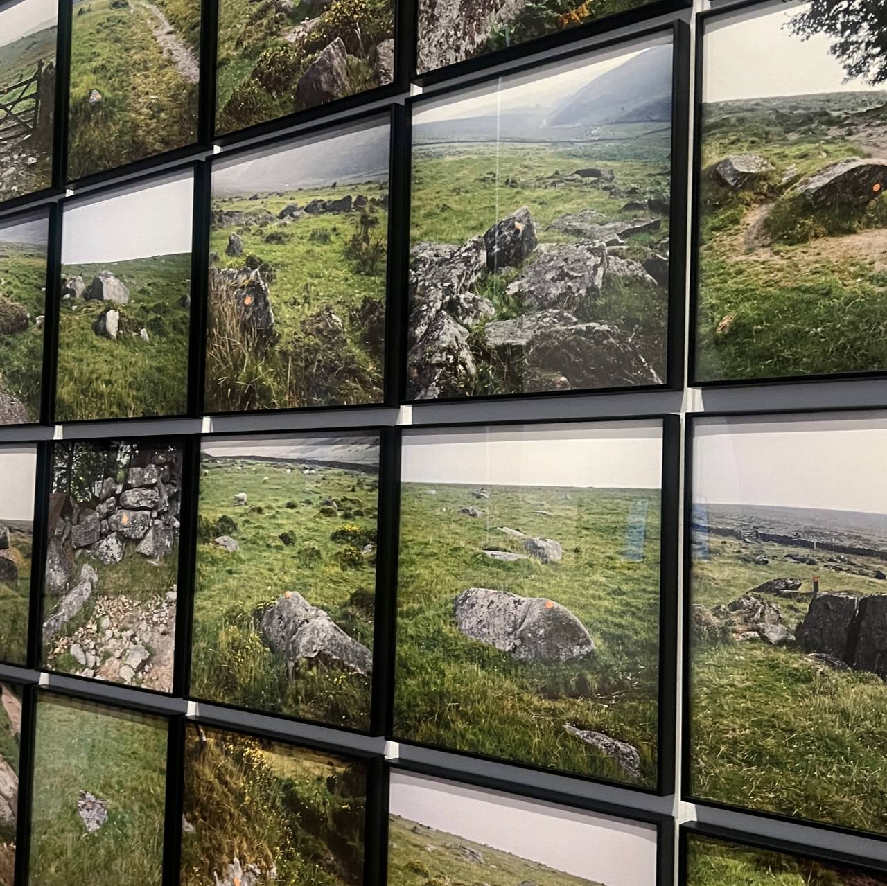 A grid of framed photographs depicting sceneries of rocky landscapes, grass, and a road, possibly reflecting a natural, rural area – each frame capturing a slightly different angle or portion of the landscape to create a larger, cohesive scene.