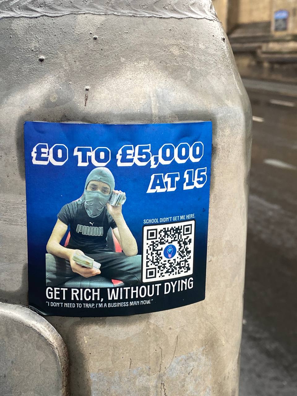 A sticker or poster adhered to a concrete surface, with a monetary growth claim from £0 to £5,000 at age 15. There’s a masked individual counting cash, a slogan "GET RICH, WITHOUT DYING," a quote at the bottom, and a QR code. The image appears to be part of an advertisement or promotional campaign.