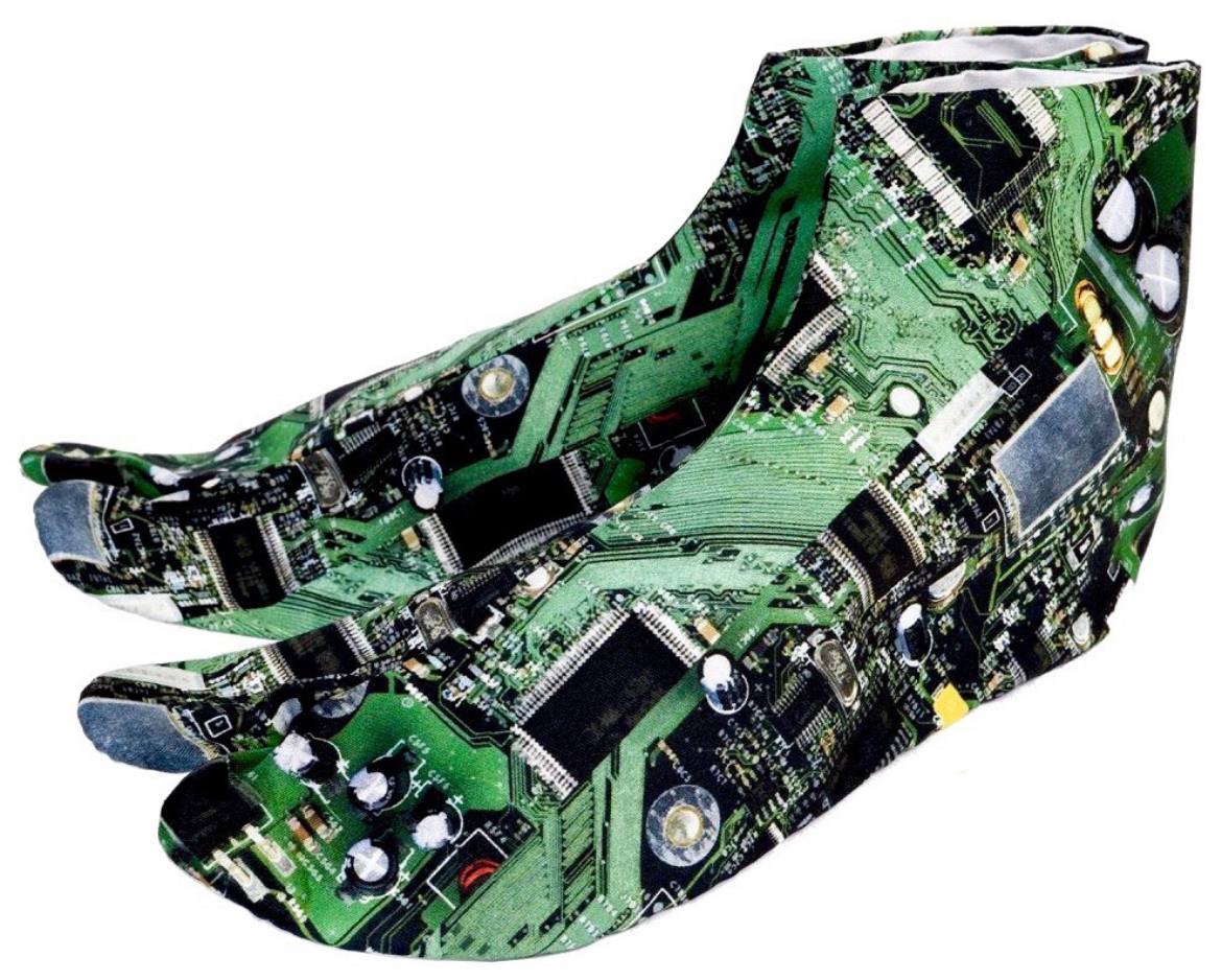 A pair of high-heeled shoes are adorned with a distinctive pattern resembling a printed circuit board. Components such as capacitors, resistors, traces, and integrated circuits are depicted, creating a unique synergy between fashion and technology.