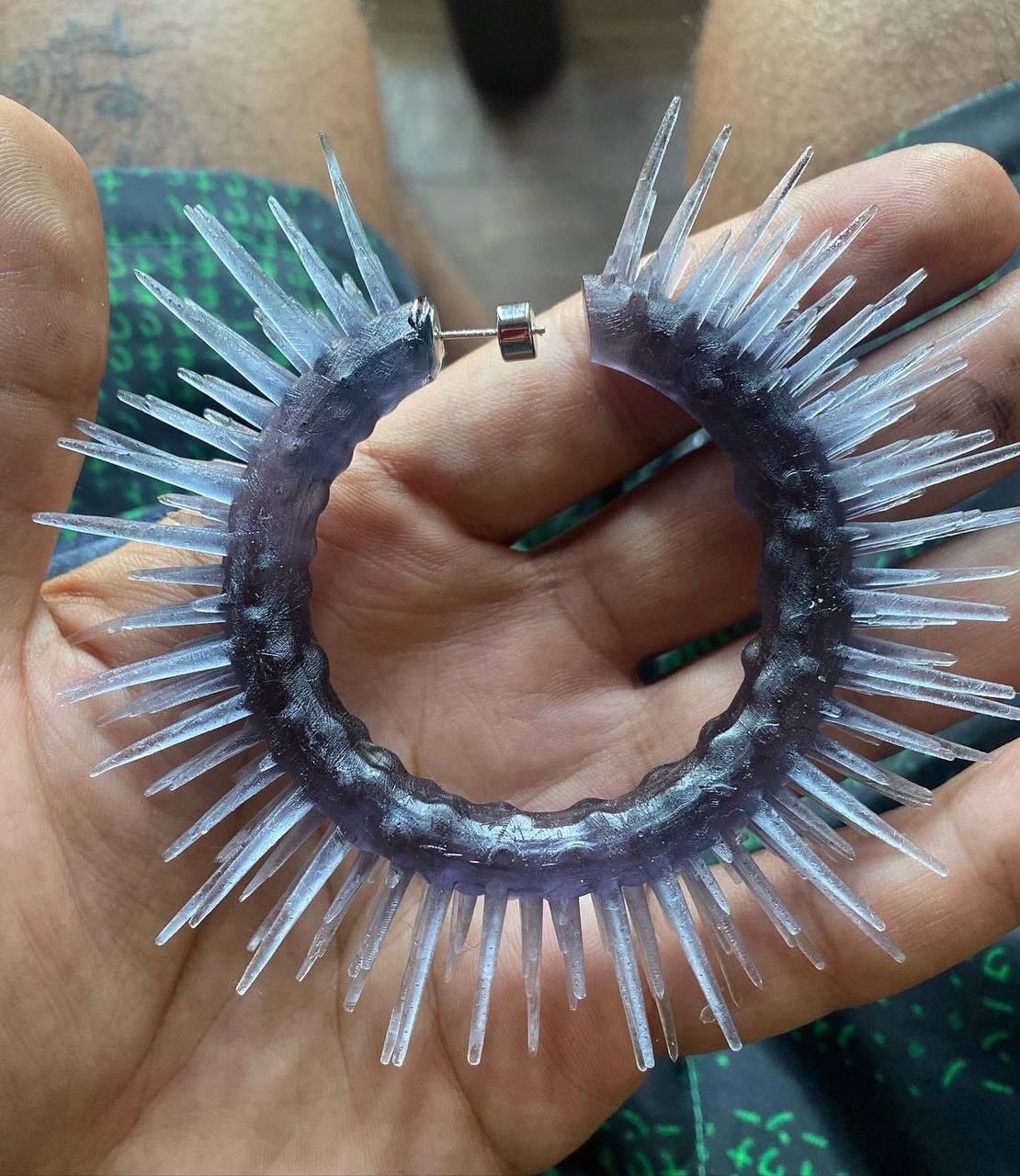 A person holds in their hand a circular-shaped object that appears to be crafted from a series of spikey protrusions emanating outward.